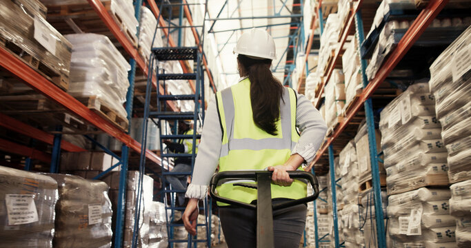 Woman, packaging and trolley in warehouse with logistics, loading bay and back for inventory management. Worker, cart and freight in storage for export, backlog control and inspection in supply chain
