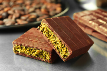 Pieces of tasty Dubai chocolate with pistachios and knafeh on grey table, closeup
