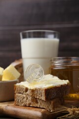 Tasty sandwich with butter, honey and dipper on wooden table, closeup
