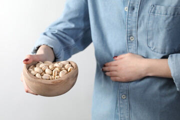 Woman refusing to eat pistachios on white background, closeup. Food allergy concept