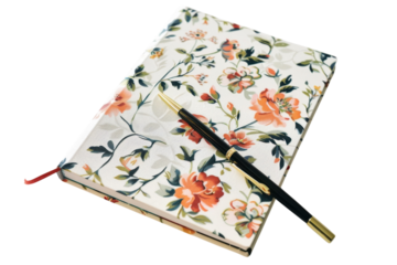 A floral-patterned journal rests elegantly on a smooth surface, accompanied by a stylish pen isolated on transparent background