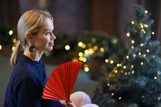 A woman with a red fan in the style of Chinese New Year