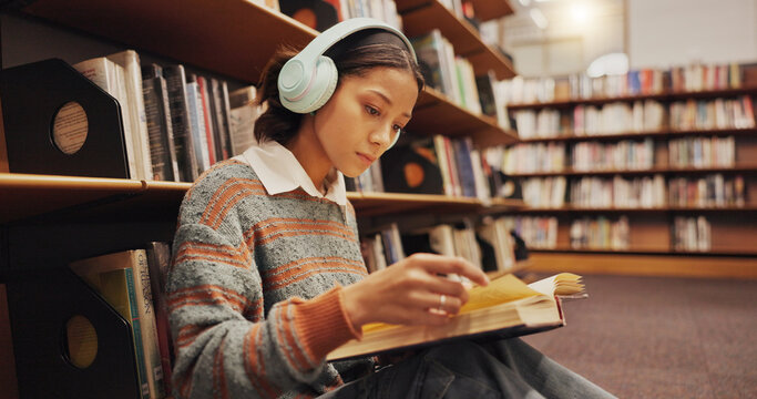 Woman, student and headphones at library with reading book on floor, study and song with scholarship at college. Girl, education and listening to music, streaming and prepare for test at university