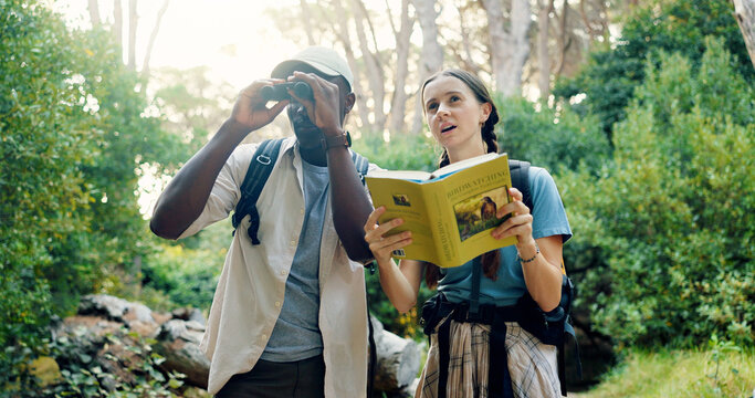 Binoculars, travel and people with birdwatching in forest, book for info and knowledge of species in nature. Friends, man and woman with sightseeing, exploring and trekking with animal text in woods