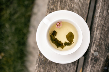 A top-down view of a white bowl with green tea tea and floating flower, placed on a rustic wooden surface. A serene composition perfect for mindfulness, slow living, and wellness photography.  