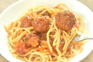 spaghetti dressing fried meatball stuffed cheese in chop onion and tomato ketchup sauce on plate  
