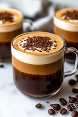 Delicious layered coffee topped with cream and chocolate shavings in a clear glass mug on a table