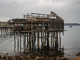 Dilapidated wooden structure on stilts over calm water