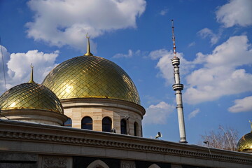 The golden dome of the mosque with a crescent moon on the background of the Kok Tobe TV tower. The...