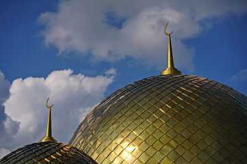 The golden dome of the mosque with a crescent moon. The minaret. Urban architecture.