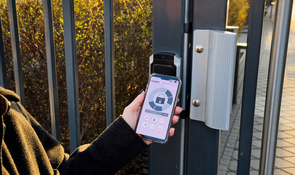 Young stylish woman getting access to the building by attaching smartphone to intercom. Concept of modern security technologies for access and smart home