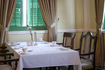 The interior of a restaurant, with white table cloth and curtains.