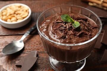 Tasty pudding with mint and pieces of chocolate served on wooden table, closeup