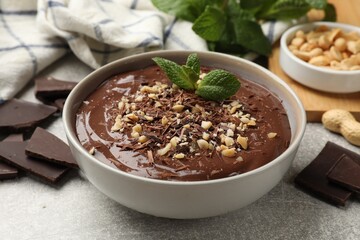 Delicious chocolate mousse in bowl grey table, closeup