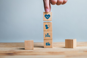 Hand Stacking Wooden Blocks with Health Icons on a Table