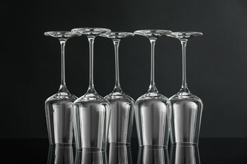 Many empty clean glasses on mirror surface against black background
