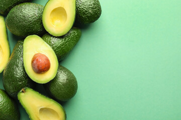 Fototapeta premium Whole and cut avocados on green background, flat lay. Space for text