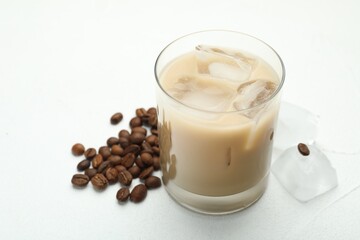 Coffee cream liqueur in glass, ice and beans on white table, closeup