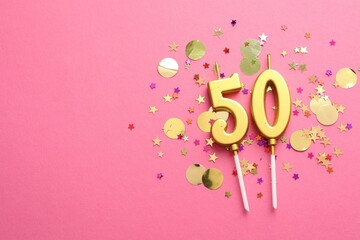 50th birthday. Number shaped candles and confetti on pink background, flat lay. Space for text