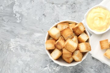 Tasty crispy croutons and sauce on grey textured table, flat lay. Space for text