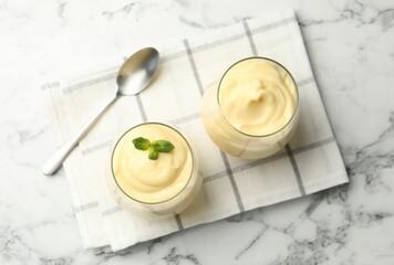 Tasty vanilla pudding with mint served on white marble table, flat lay
