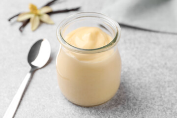 Tasty vanilla pudding, pods and flower on grey table, closeup