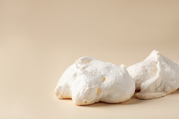Delicious homemade meringue cookies on beige background, closeup. Space for text