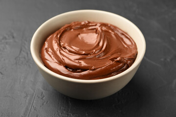 Tasty chocolate pudding in bowl on black table, closeup