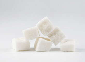 Several pieces of white crushed sugar on a white background. White on white.