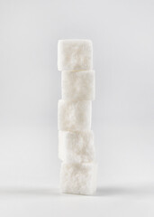 Tower of white crushed sugar pieces on white background. White on white.