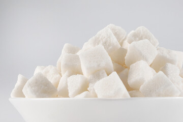 White plate with pieces of crushed white sugar on white background. white sugar on white.