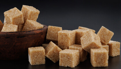 Brown sugar cubes on black background. Cane sugar.