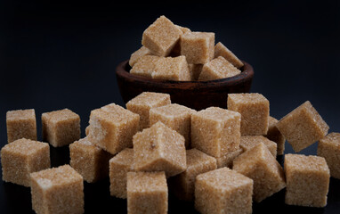 Cane brown sugar on a black background. Sugar cubes.