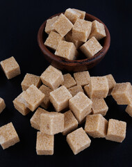 Cane brown sugar on a black background. Sugar cubes.