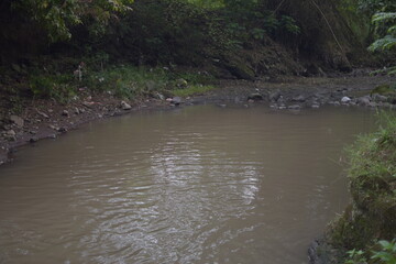 A foamy, murky river flows through a rocky landscape