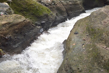 Obraz premium A foamy, murky river flows through a rocky landscape