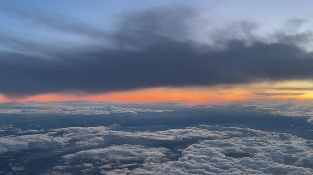 an aerial view from a jet cockpit of a fire sunrise with layers of fluffy clouds, as seen from a jet cockpit by the pilots.