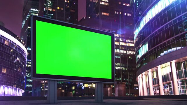 Green screen billboard displaying advertisement at night in a modern city