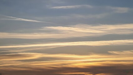 Obraz premium A breathtaking sunset over a cloudy sky, with the airplane's contrails creating a spectacular view against the fading daylight.