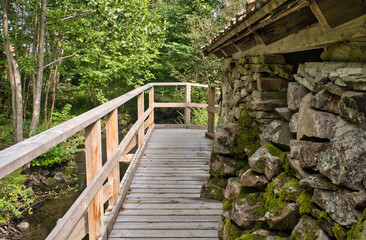 Fototapeta premium Old watermill surrounded by green nature. Moss-covered stones, surrounded by trees.