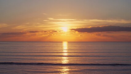 Naklejka premium Calm waves and golden sunset horizon.