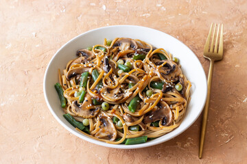 Udon noodles in teriyaki sauce with mushrooms, beans and peas. Asian cuisine. Vegetarian food.