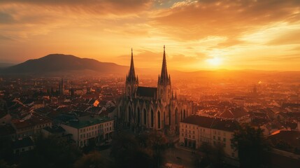 Breathtaking aerial view of a historic cathedral at sunset, with a towering mountain in the distance.