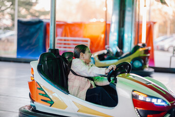 Happy girl driving bumper car at amusement park