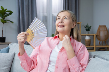 Mid aged woman in pink shirt with a fan in hands