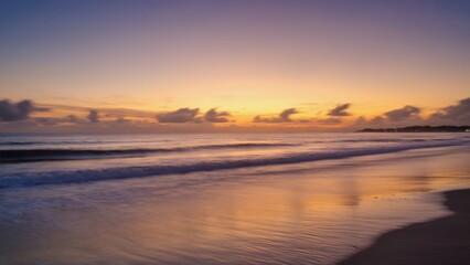 A tranquil beach scene at sunset, with the ocean waves lapping onto the shore, reflecting a soft glow from the sky.
