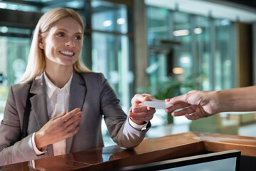 Businesswoman handing key card at office reception desk in lobby