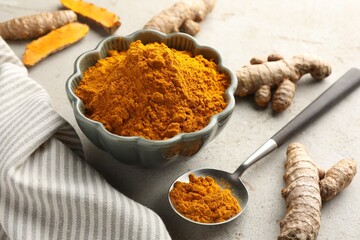 Aromatic turmeric powder in bowl and fresh roots on light grey table, closeup