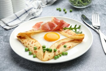 Delicious crepe with egg, bacon, arugula and green peas on grey table, closeup