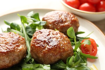 Delicious patties with greens and tomato on table, closeup